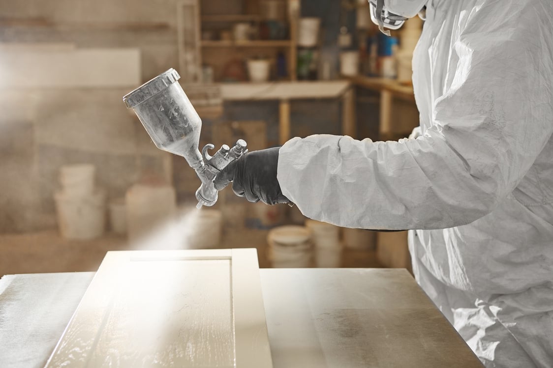 Close-up of industrial worker using paint gun or spray gun for applying paint, airless spraying.